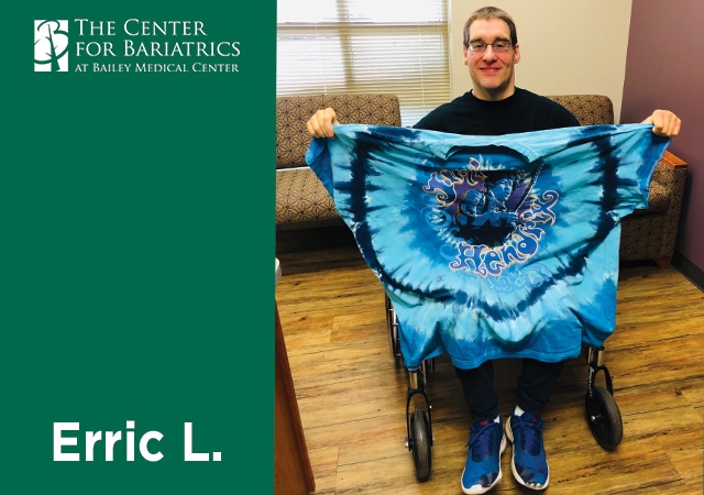 Erric holding up a shirt several sizes too large