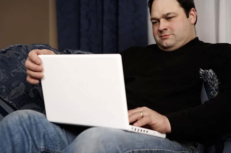 over weight man looking at his laptop