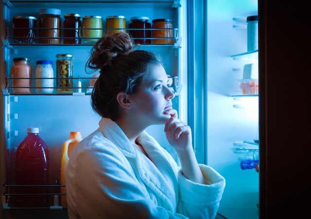 woman in her robe staring into her open fridge